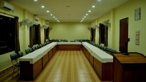 Un salón de conferencias con una larga mesa, sillas y ventiladores de techo.