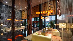 A modern lobby with a reflective floor, seating areas, and decorative lighting. - Jasmine International Hotel (Changsha)
