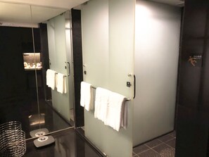 A modern bathroom with glass partitions, a scale, and a hand sanitizer dispenser. - Jasmine International Hotel (Changsha)