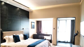A modern hotel room with a large bed, a desk, and a view of the outdoors. - Jasmine International Hotel (Changsha)