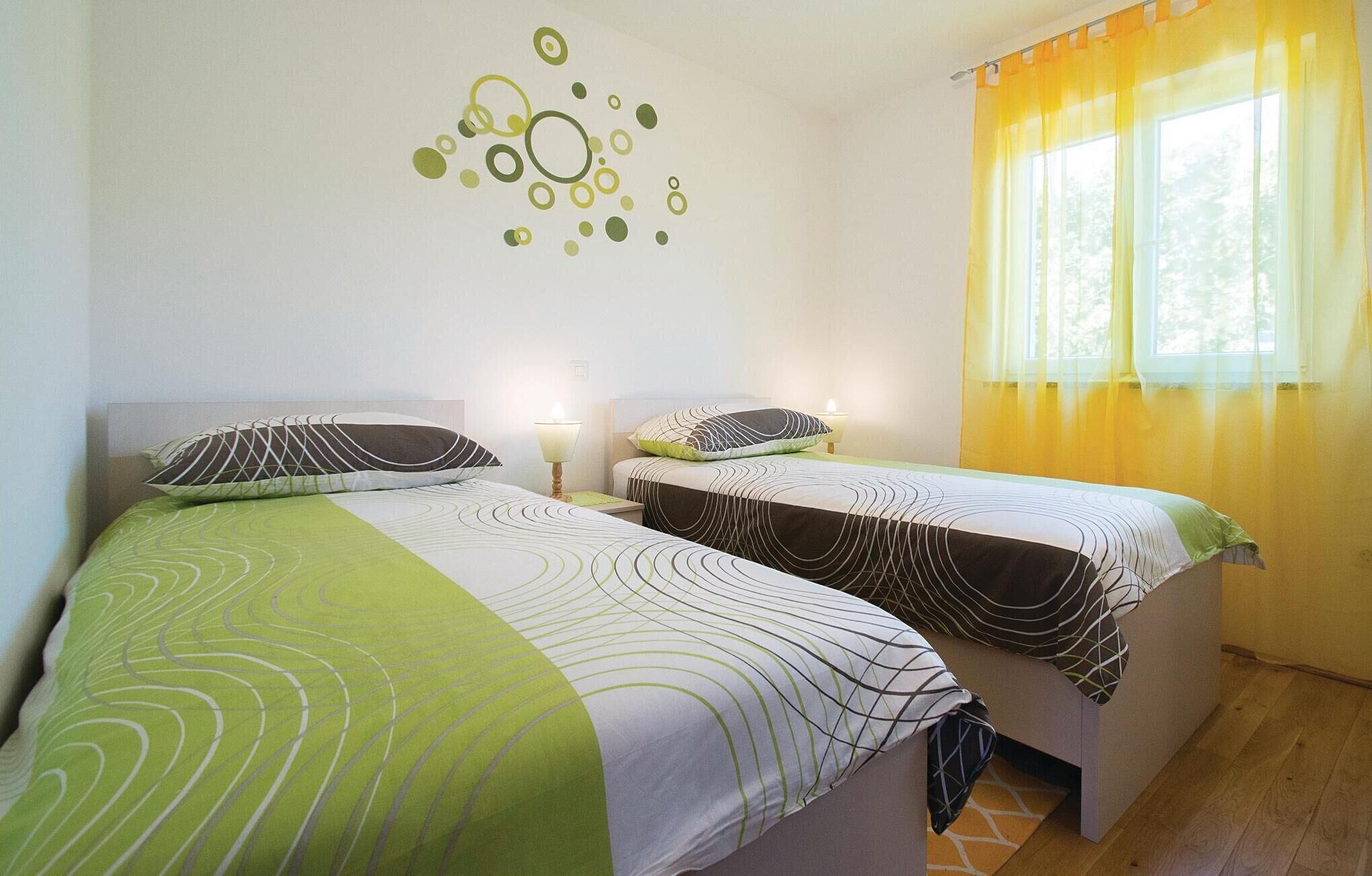 Ein Doppelzimmer mit zwei Betten, jeweils mit gemusterten Bettbezügen und einer Wanddekoration.
