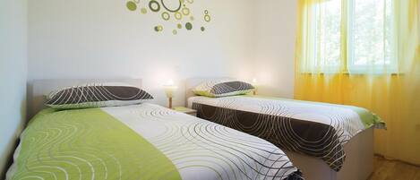 Ein Doppelzimmer mit zwei Betten, jeweils mit gemusterten Bettbezügen und einer Wanddekoration.