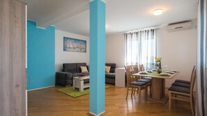 A modern living room with a dining area, featuring a wooden floor, a blue accent wall, and a painting. - Stunning apartment in Labin with house sea view (Labin)