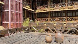 A wooden table with two pottery vases, a decorative fence, and a building with intricate wooden railings and windows.