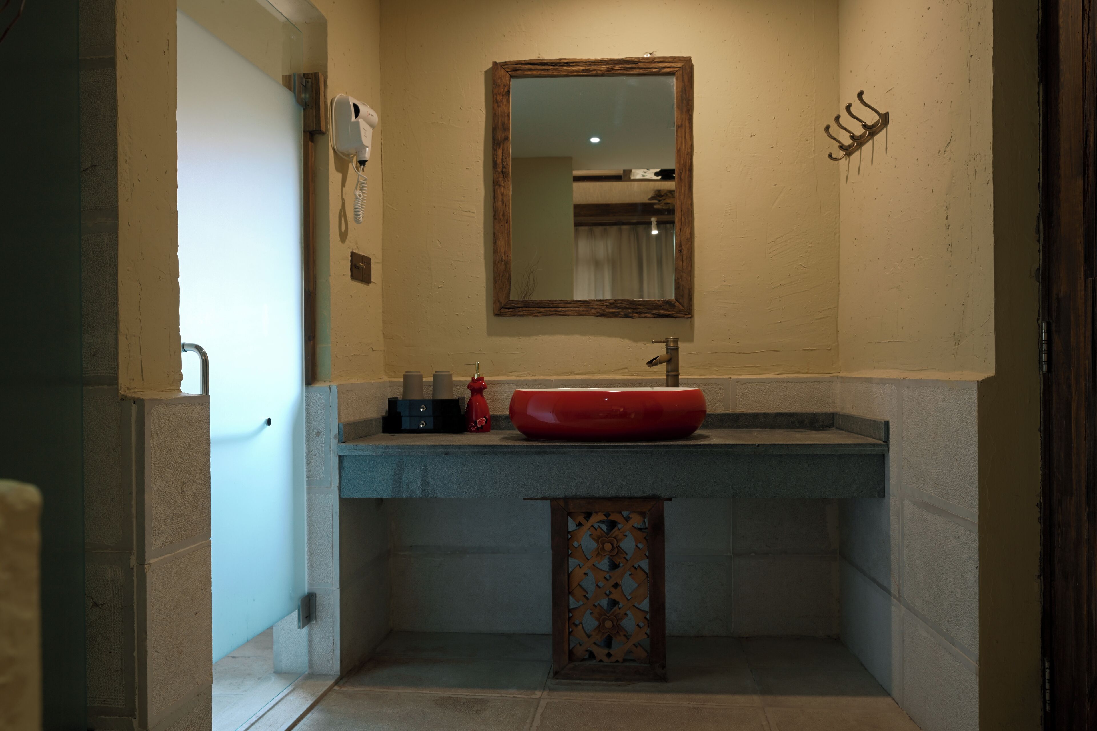 A bathroom with a red sink, a mirror, a towel rack, and a small cabinet.
