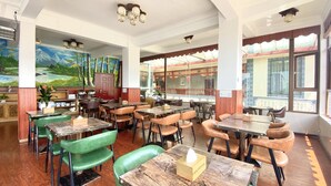 A restaurant with wooden tables and chairs, a mural on the wall, and large windows.