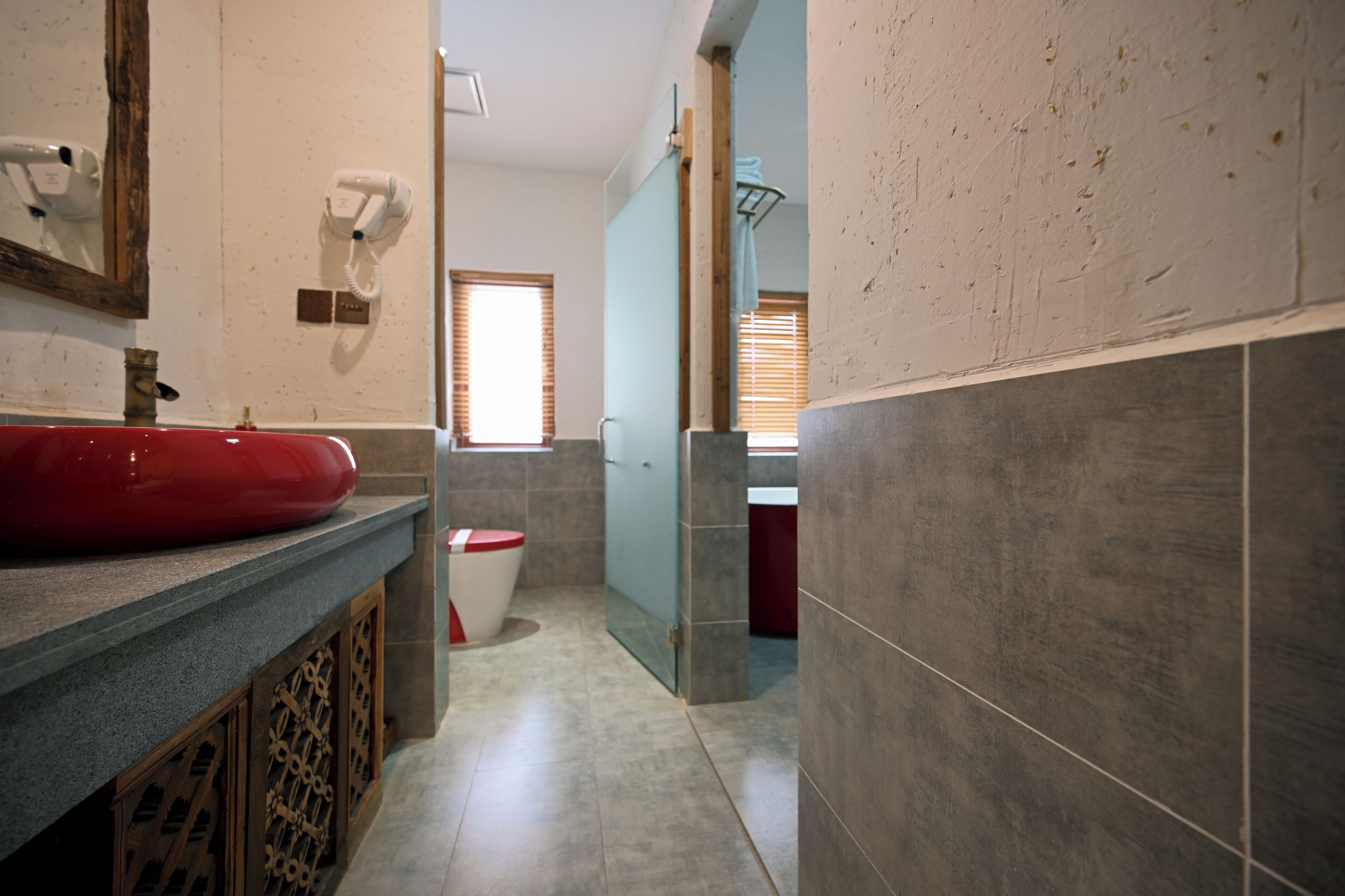 A bathroom with a red sink, a mirror, a hairdryer, and a towel rack.