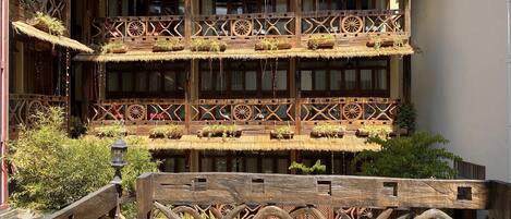 Un edificio de madera tradicional con varios balcones, cada uno decorado con techos de paja y barandales de madera.