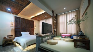 A bedroom with a bed, a TV, a sofa, and a decorative wall panel.