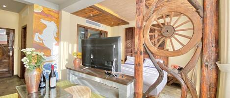 Una sala de estar con una rueda de madera, un televisor de pantalla plana y un mural de un mapa.