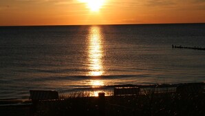 Auringonlasku valtameren yllä, ja laiturin pää ulottuu veden äärelle.