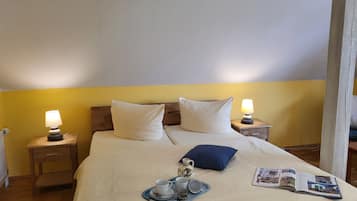 Een keurig opgemaakt bed met kussens, een dienblad met kopjes en een kan, en een tijdschrift op het bed.