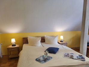 A neatly made bed with pillows, a tray with cups and a jug, and a magazine on the bed.