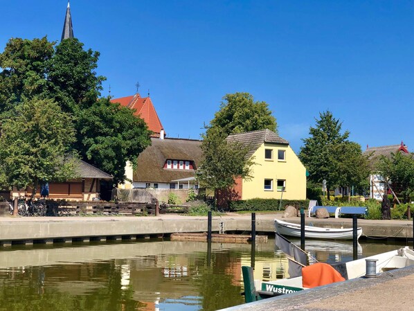 A canal with boats docked, a church spire, and traditional houses.