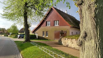 Een huis met een rood dak, een verharde oprit en een fietsenrek van metaal.