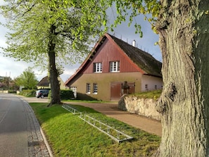 A red-roofed house with a paved driveway and a metal bike rack.