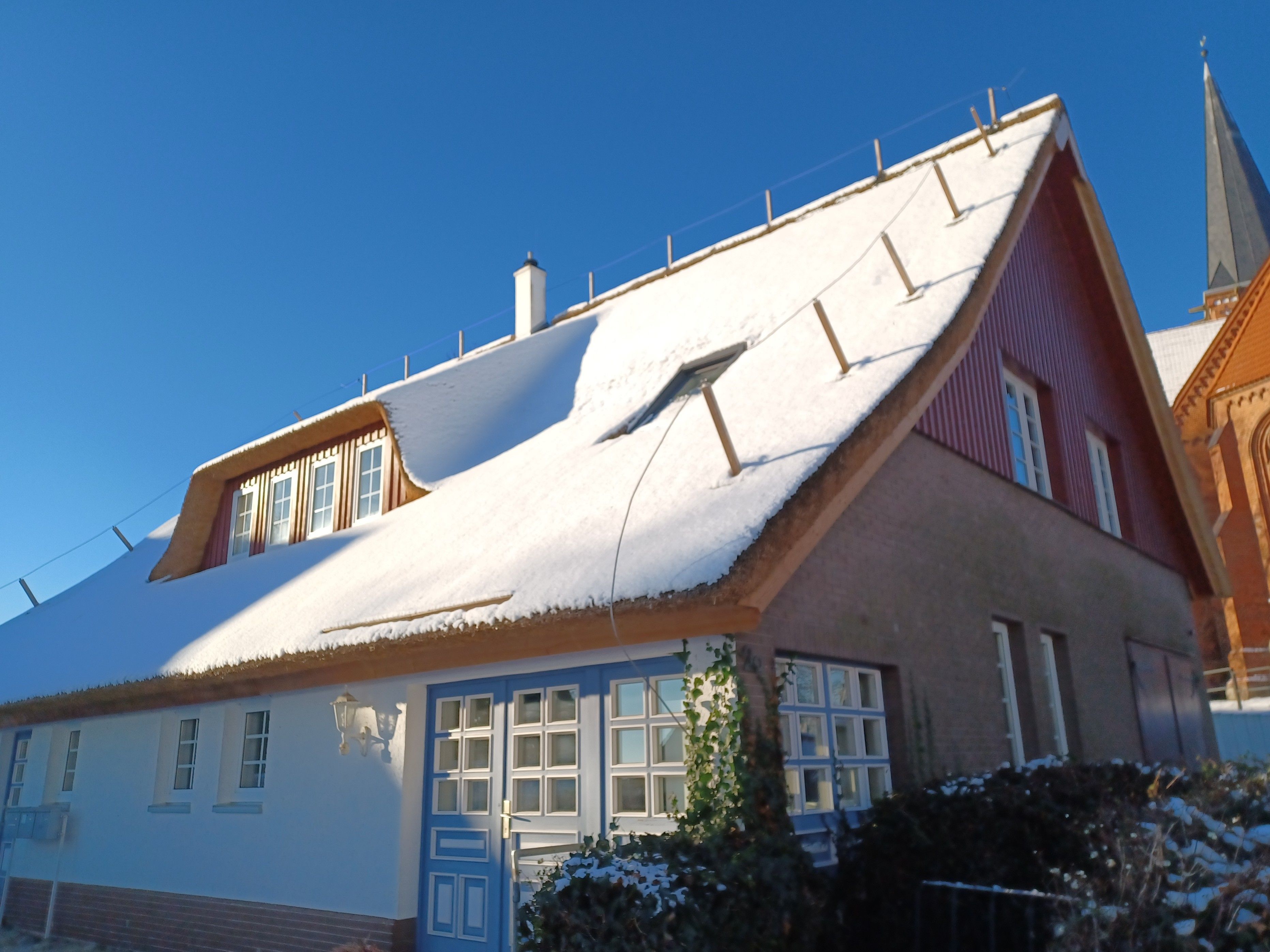 Ein traditionelles Haus mit steilem Dach, zahlreichen Fenstern und einem markanten Schornstein.