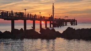 Une jetée qui s’avance dans l’eau, avec un coucher de soleil en arrière-plan.