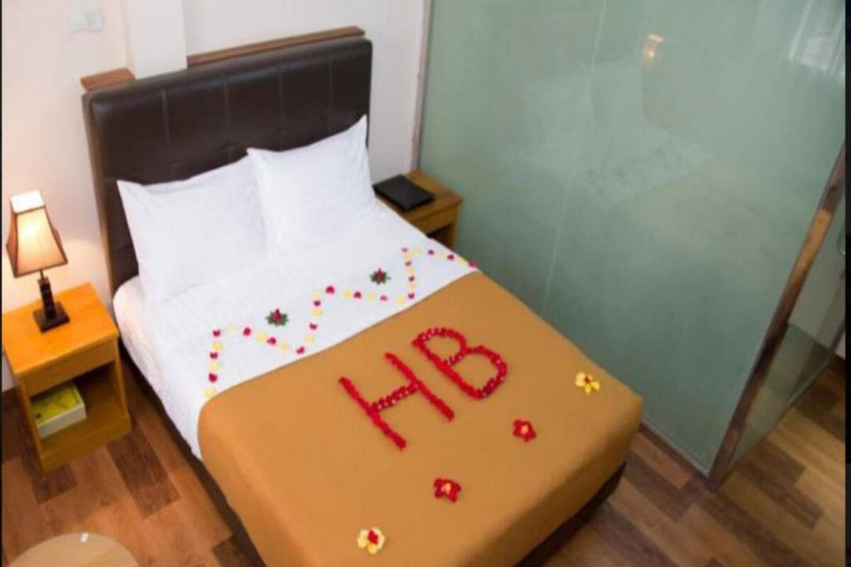 A hotel room with a bed, a nightstand, a lamp, and a small round table.