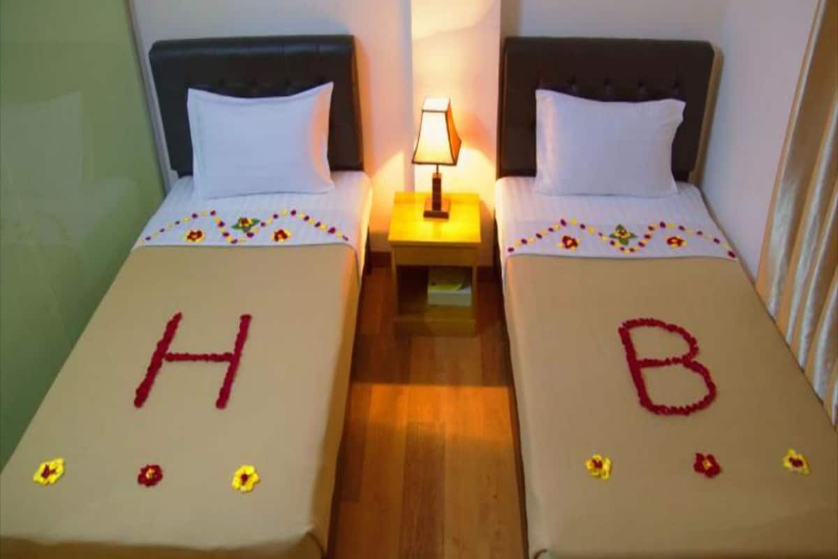 Two single beds with floral decorations and letters 'H' and 'B' on the beds.