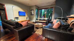 Een moderne woonkamer met leren banken, een houten salontafel, een televisie en een open haard.