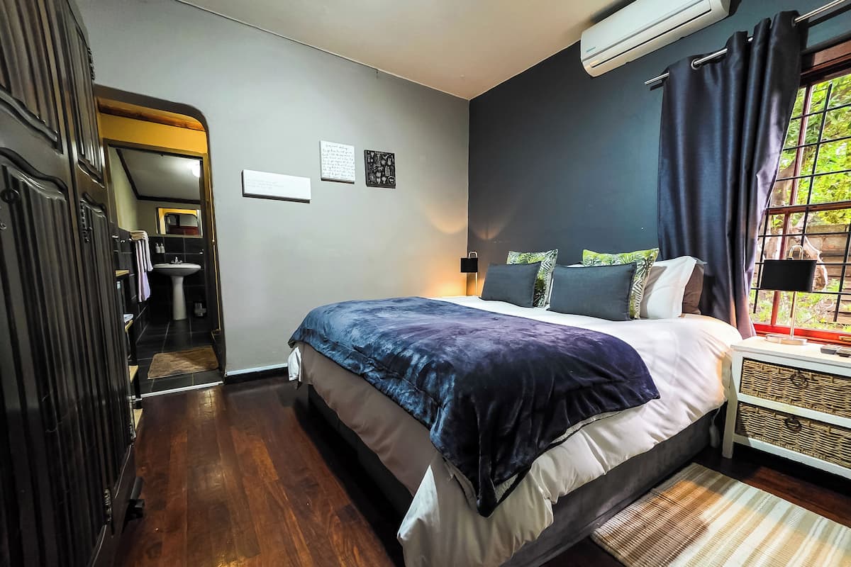 Un dormitorio con cama, mesita de noche y ventana con cortinas.