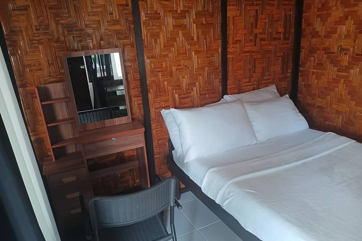 A room with a bed, a desk with a mirror, and a chair.