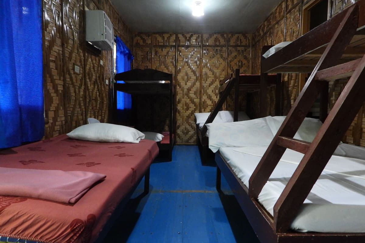 A room with two bunk beds, a blue floor, and a patterned wall.