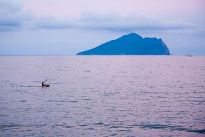 A kayaker on calm waters with a large island in the background. - noir B&B (Toucheng)