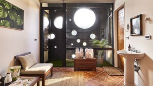 A modern room with a sofa, a coffee table, a sink, and a view through a door with circular cutouts. - noir B&B (Toucheng)
