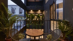 A balcony with a round table and chairs, surrounded by potted plants. - noir B&B (Toucheng)