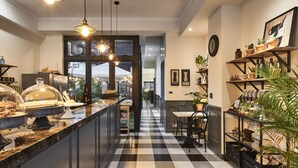 A hotel corridor with a checkered floor, pendant lighting, a view into another room, and shelves with various items. - noir B&B (Toucheng)
