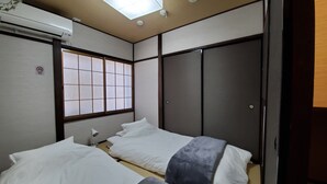 A traditional Japanese-style room with tatami flooring, a shoji screen window, a ceiling fan, and a wardrobe. - Hana Botan (Kyoto)