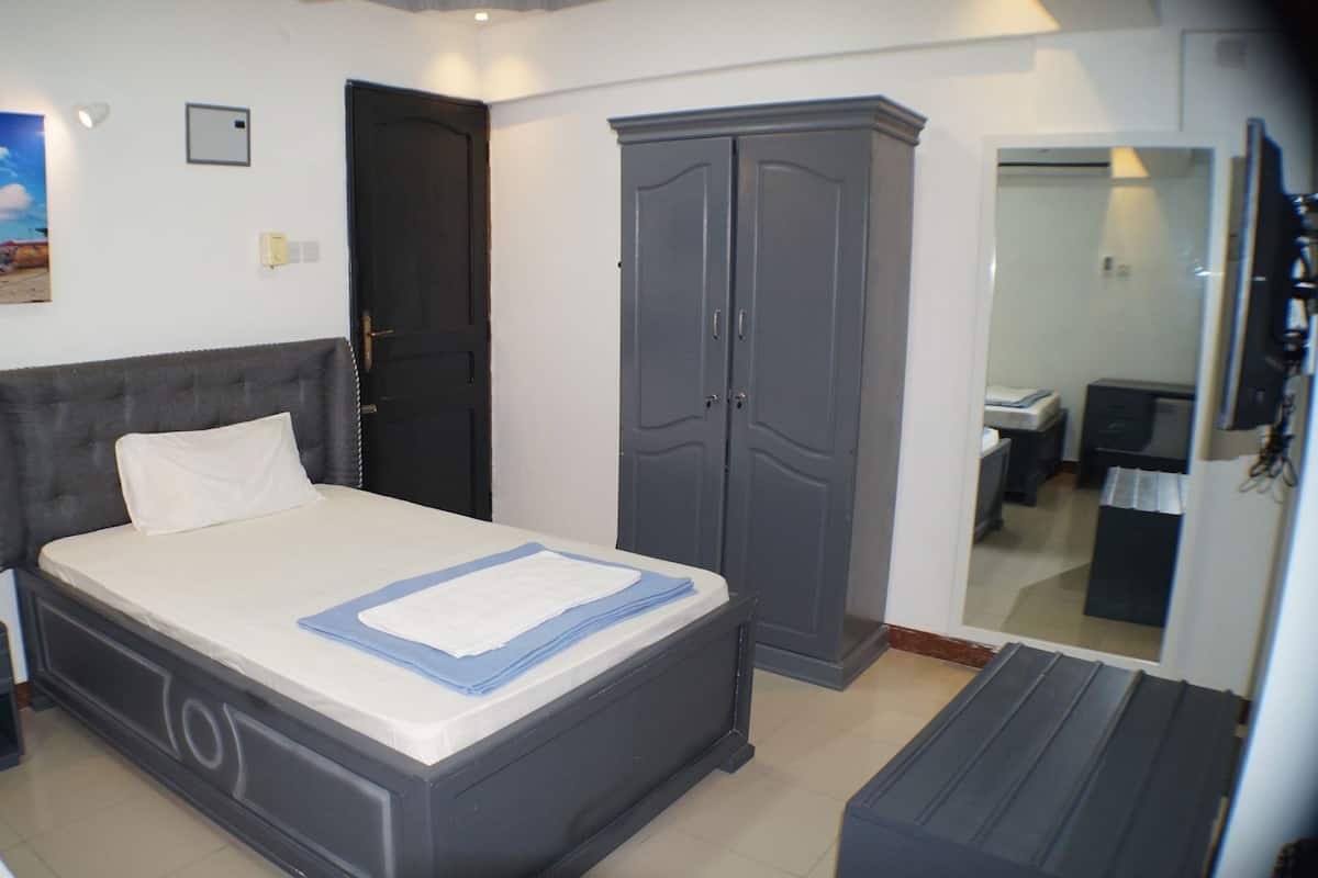 Un dormitorio con cama, armario, escritorio y espejo.