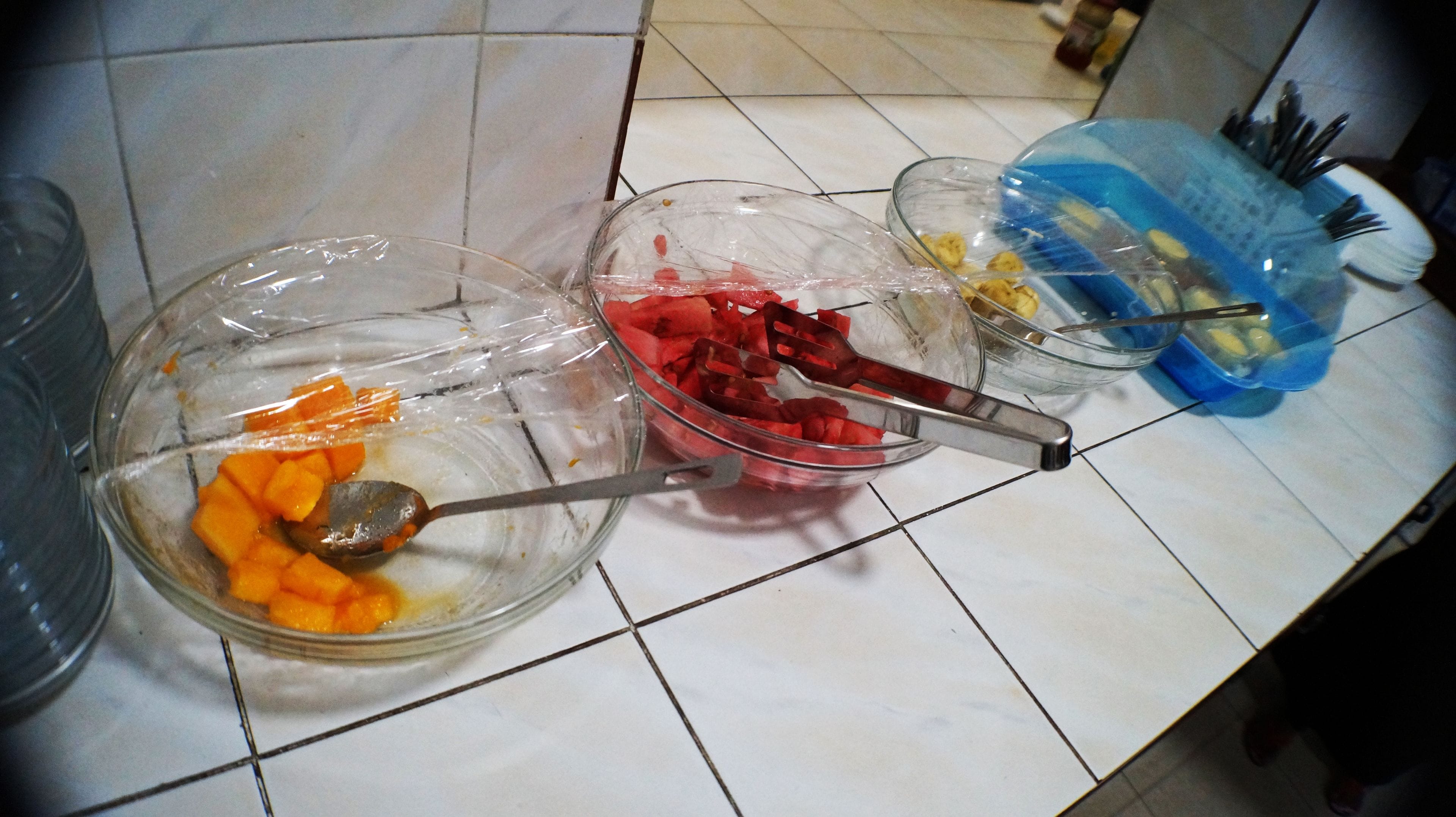 Three glass bowls with food on a tiled countertop.
