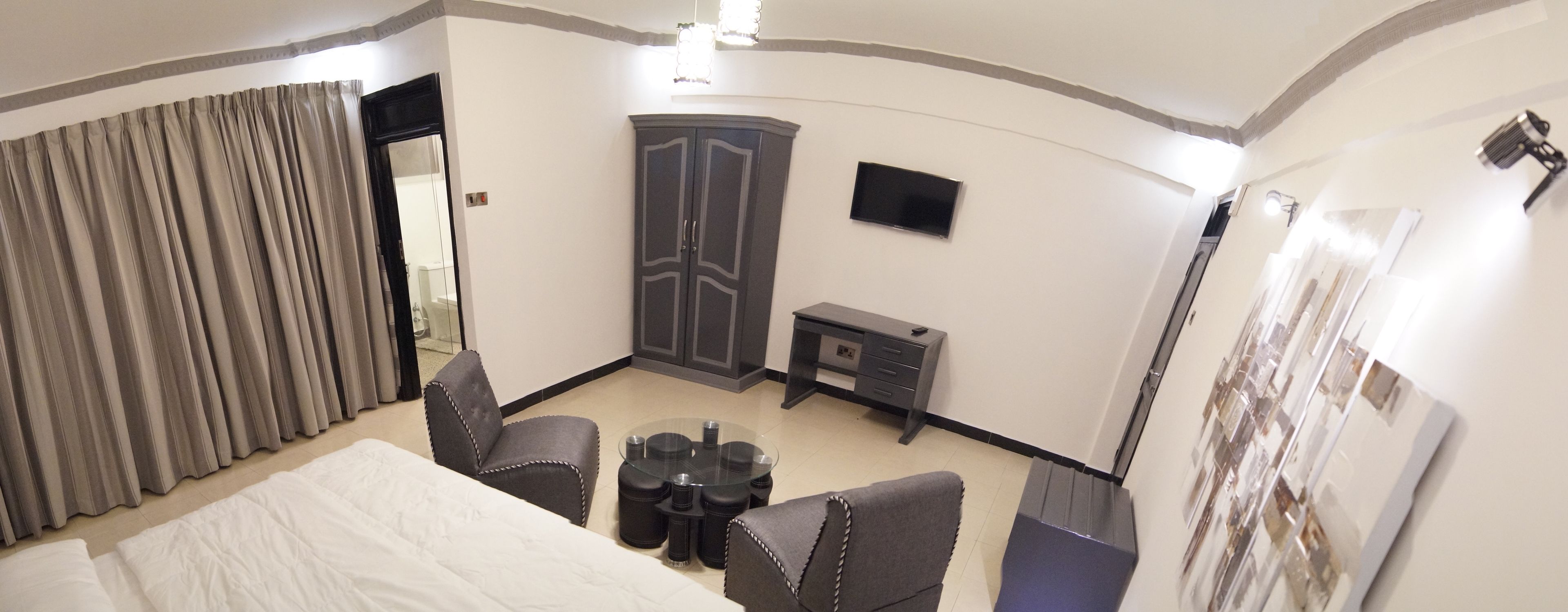 A hotel room with a bed, a desk, a chair, a small table, and a wardrobe.