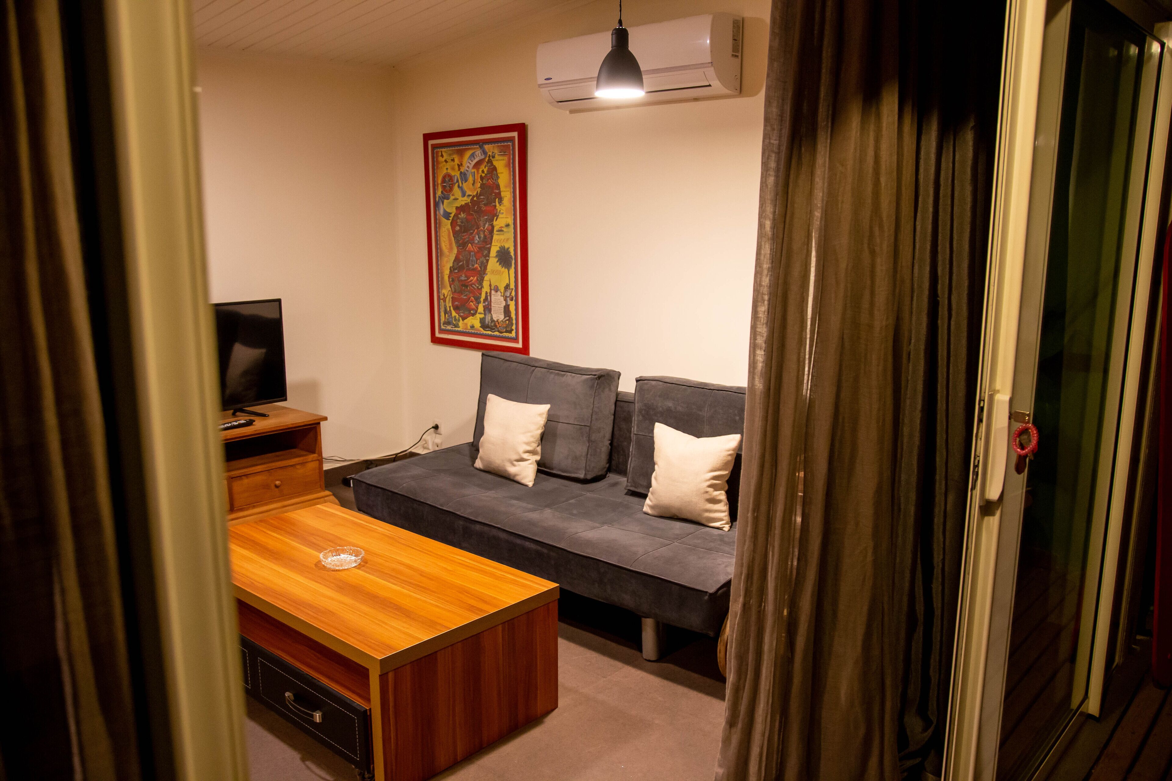Una habitación con una mesa de madera, un sofá gris y una televisión.