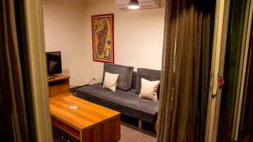 Una habitación con una mesa de madera, un sofá gris y una televisión.