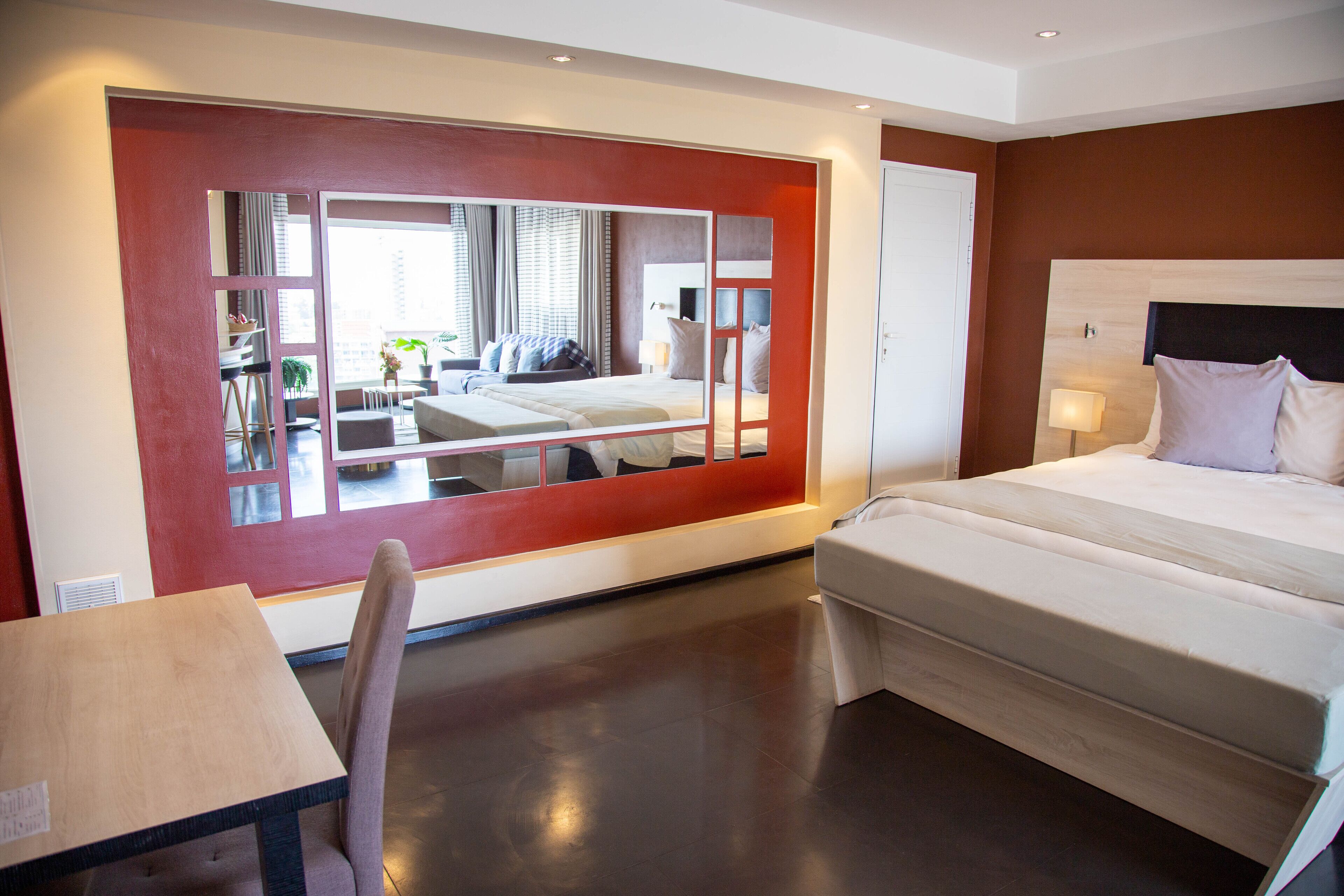 Una habitación de hotel moderna con una cama grande, un escritorio y un espejo que refleja la habitación.