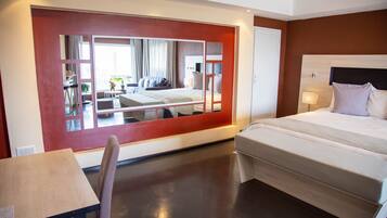 Una habitación de hotel moderna con una cama grande, un escritorio y un espejo que refleja la habitación.