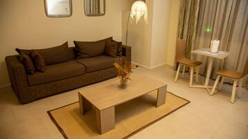 Una sala de estar con un sofá, una mesa de centro, una lámpara y una silla.