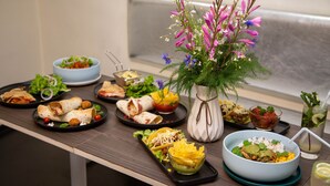 En buffet med forskellige retter, herunder salater, skåle og en blomsterdekoration.