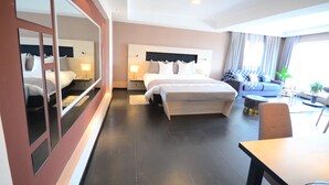 Et moderne hotelværelse med en stor seng, en sofa, et spisebord og et spejl.