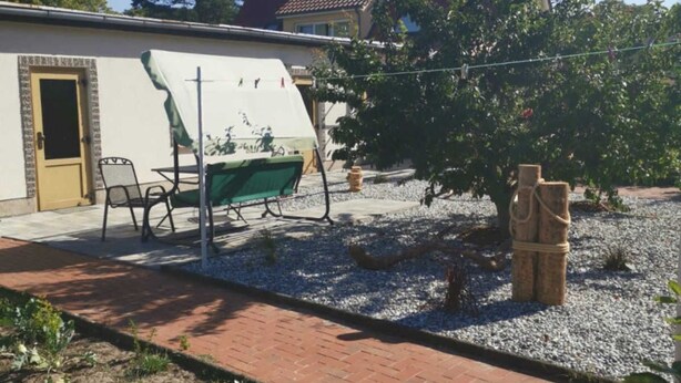 A garden area with a paved walkway, a covered outdoor seating area, and a statue. - Vacation apartment MAXIM - Holiday apartments (Koserow)