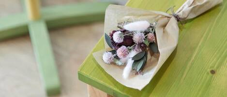 A bouquet of flowers wrapped in brown paper tied with a string, placed on a green wooden bench.