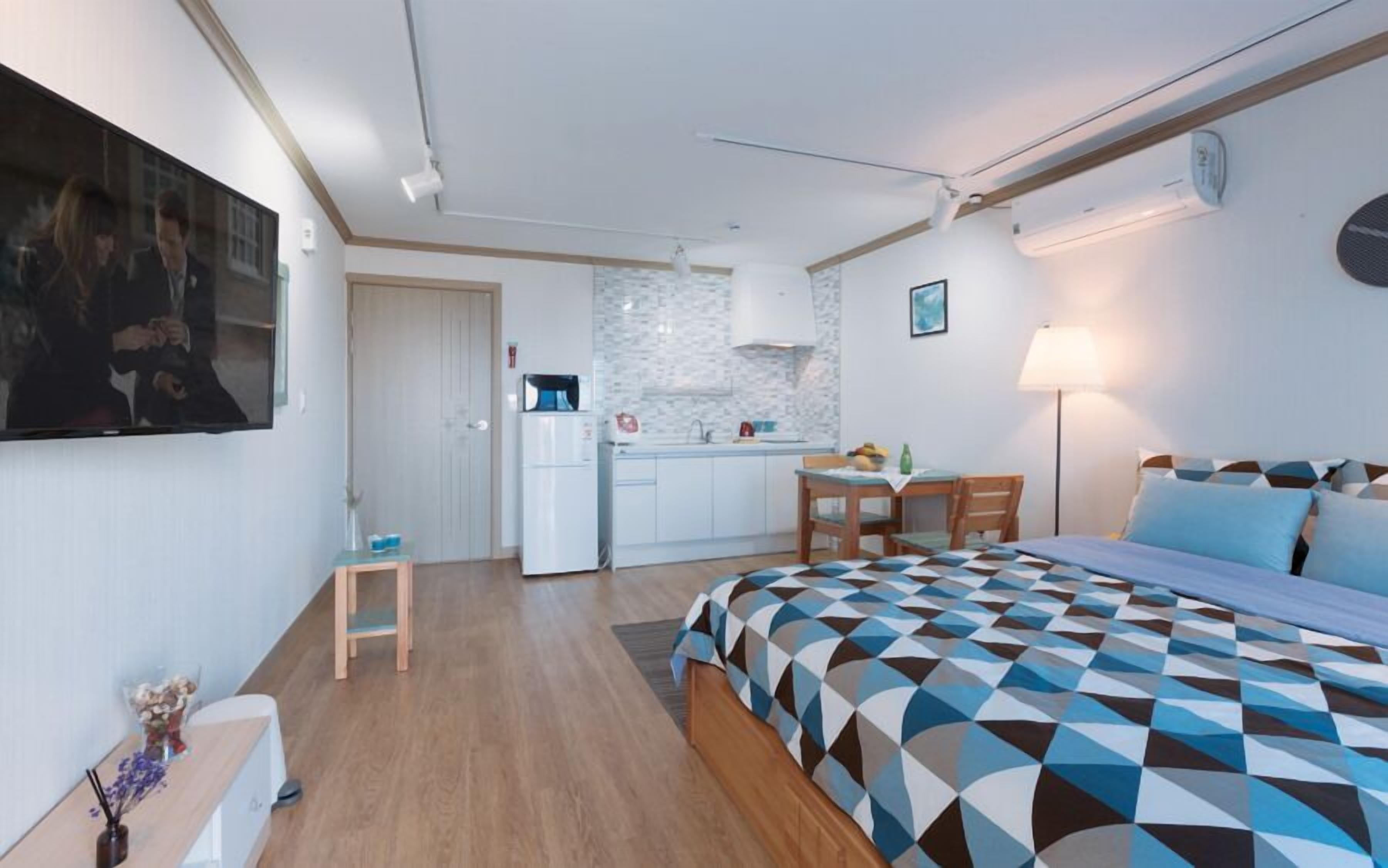 Ein kompaktes Hotelzimmer mit Bett, einer kleinen Küchenzeile, einem Essbereich und einem Badezimmer.
