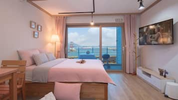 Relax in a stylish room with a large bed, TV, and balcony offering a view of the sea and a bridge.