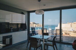 A modern kitchen with a large window overlooking a coastal view. - Sally Port Senglea (Senglea)