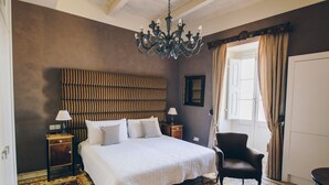 Une chambre à coucher avec un grand lit, un lustre, une chaise et une porte.
