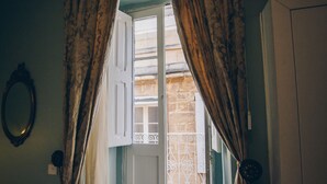 Une pièce avec une porte donnant sur un balcon, un miroir au mur et des rideaux.